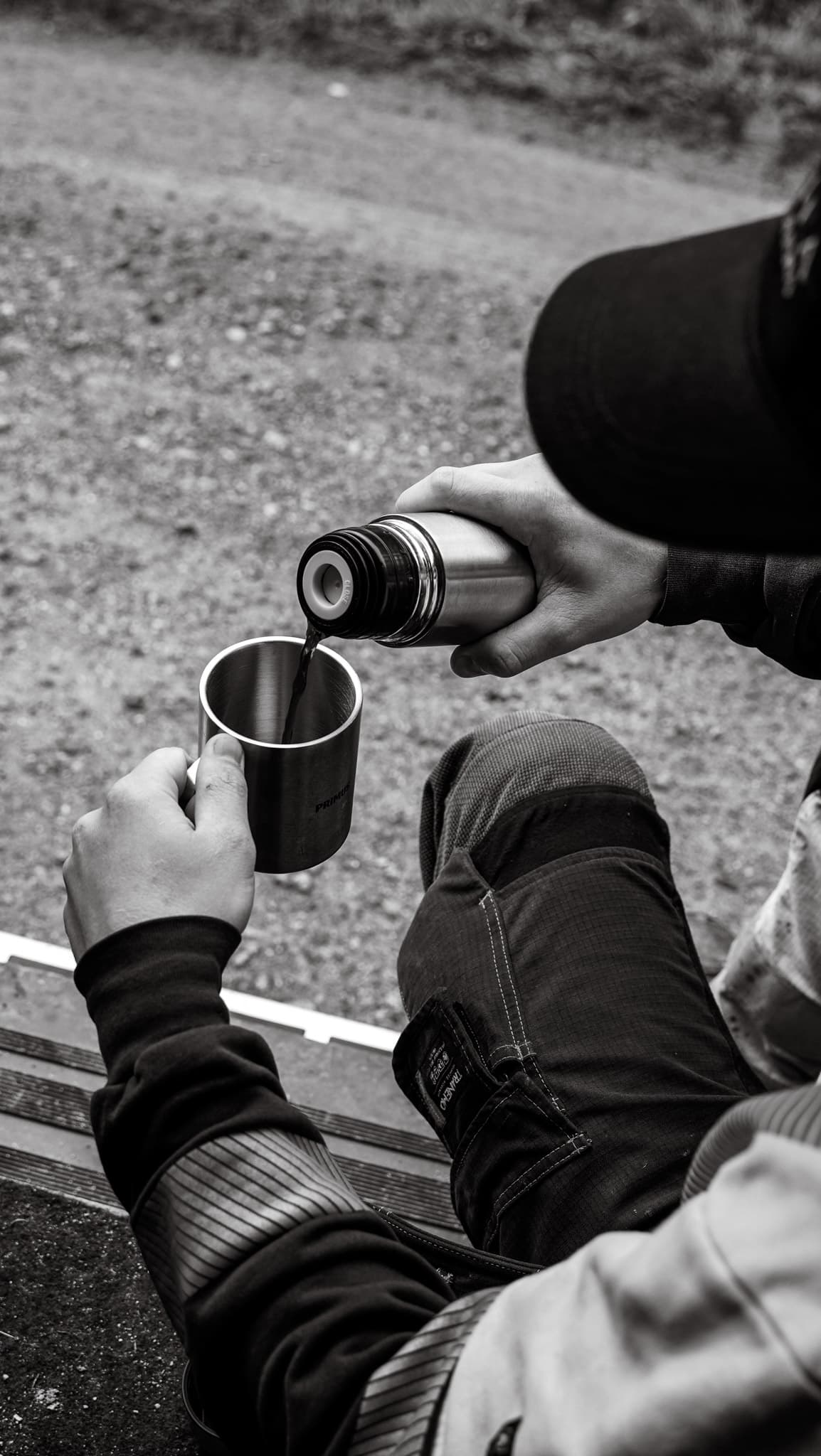 Kaffe hälls upp ur en kaffetermos, svartvit bild på en medarbetare på BTEA som tar en rast.