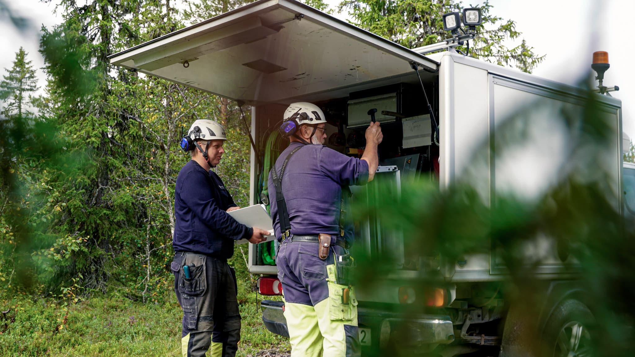 Två medarbetare vid ett arbetsfordon. Vi på BTEA ansluter din fastighet till elnätet.